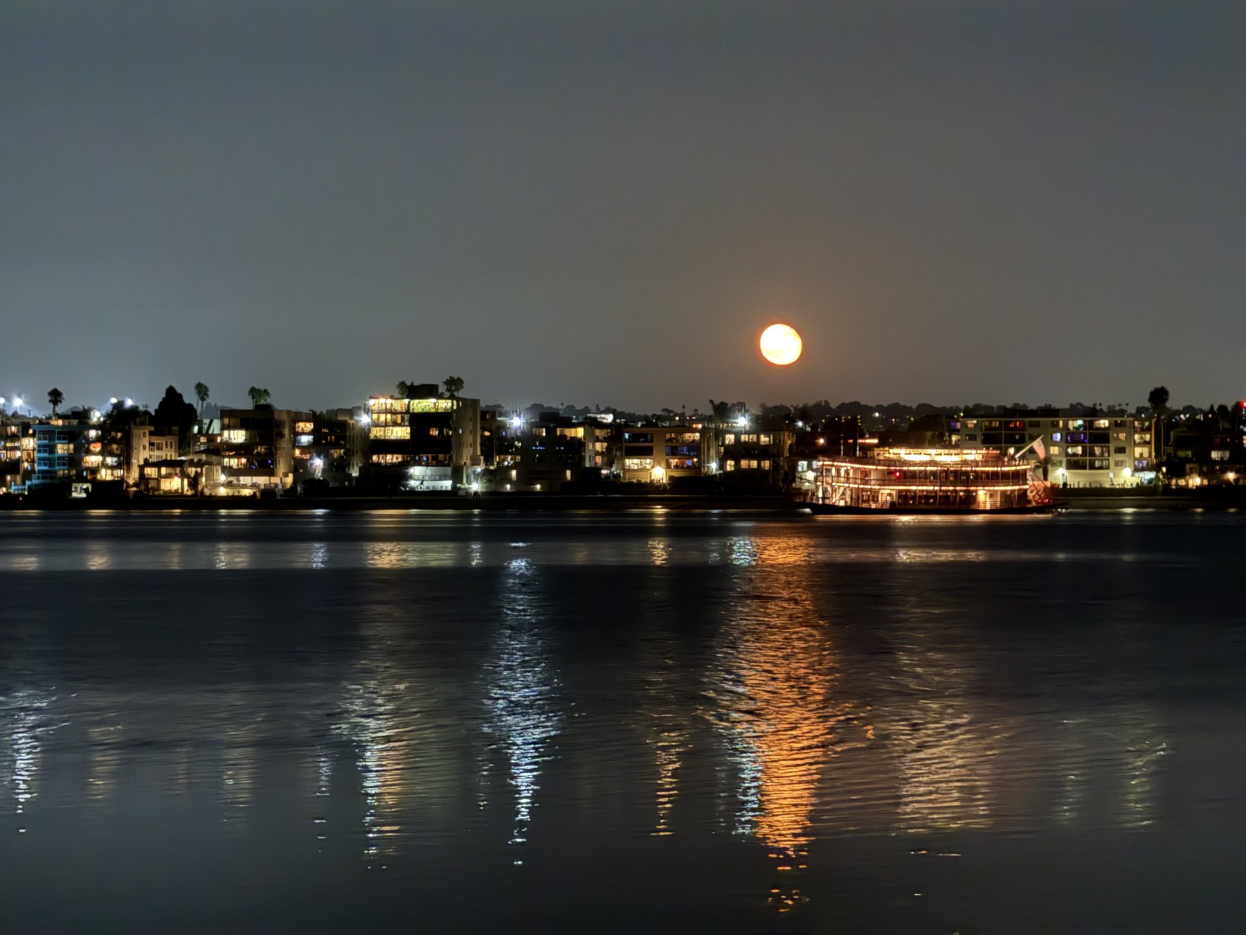 The moon rising over Mission Bay at night, seen from the water